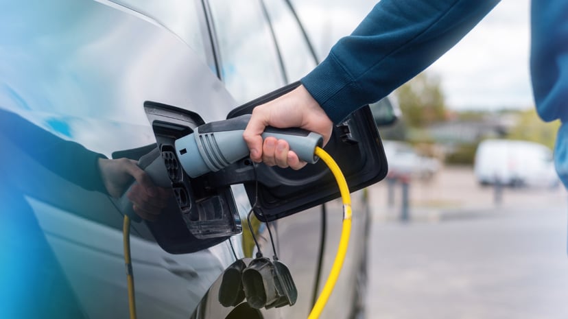Man Plugging Charger Into Electric Car Charge Station