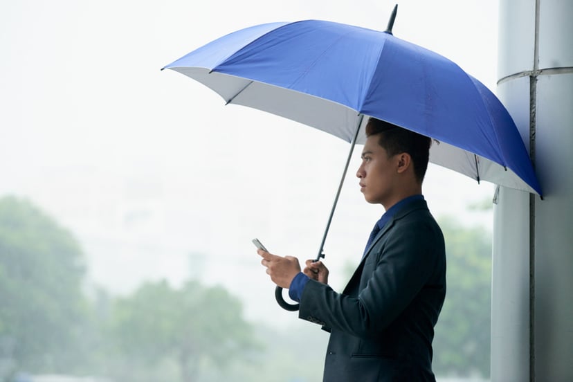 Asian Businessman Standing Street With Umbrella During Rain Using Smartphone