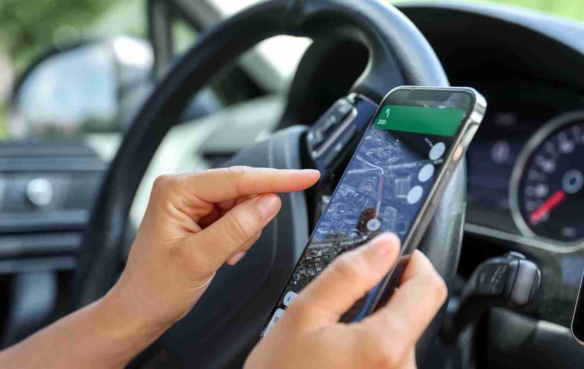 Editors%2 Fimages%2 F1702526917882 Female Driver Hand Holding Phone With Interface Navigator Screen