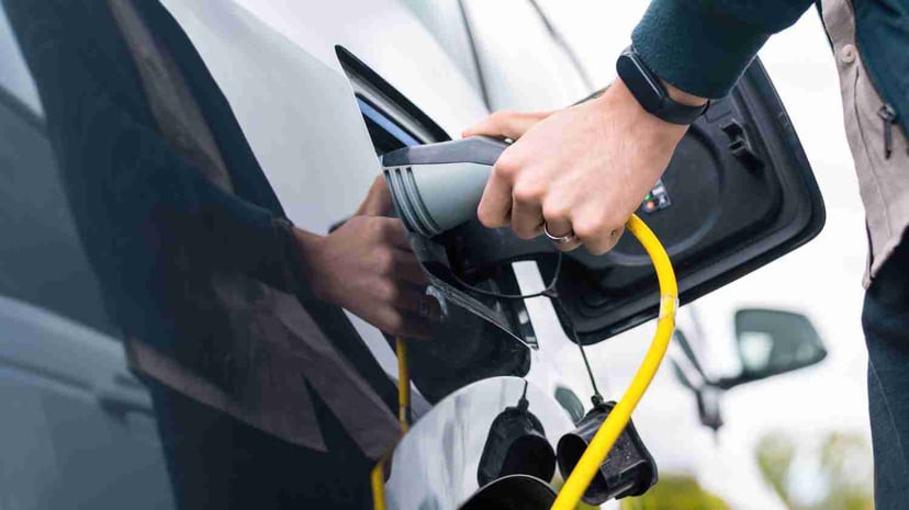 Man Plugging Charger Into Electric Car Charge Station